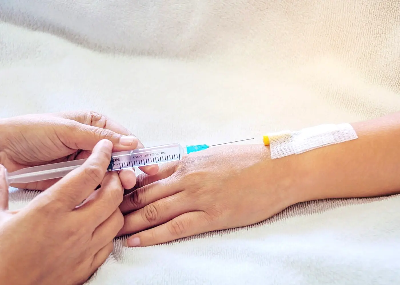 Hands preparing a vitamin injection for intravenous therapy, highlighting the importance of wellness.